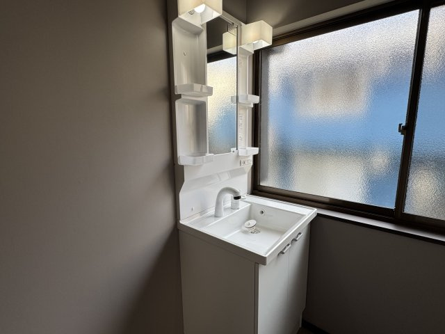 明るい窓から自然光が差し込む洗面室は、朝の身支度も快適。　鏡の両サイドに収納棚を備え、洗面用品をスッキリ整理できます。　清潔感のあるデザインで、毎日の暮らしに心地よさをプラスしてくれる空間です。