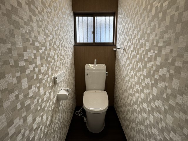 壁紙が印象的なトイレは、落ち着きと清潔感を兼ね備えた空間です。　窓があることで自然光が入り、明るく爽やかな印象に。　換気もしやすく、快適に使用できます。デザイン性と機能性を両立したトイレです。