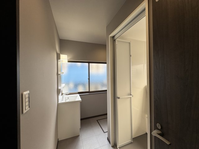 明るい光が差し込む洗面脱衣所は、清潔感あふれる空間です。　洗面台と脱衣スペースが確保され、朝の身支度やお風呂上がりも快適。　窓付きで換気も良い設計です。日常の暮らしに心地よい清潔感をもたらします。