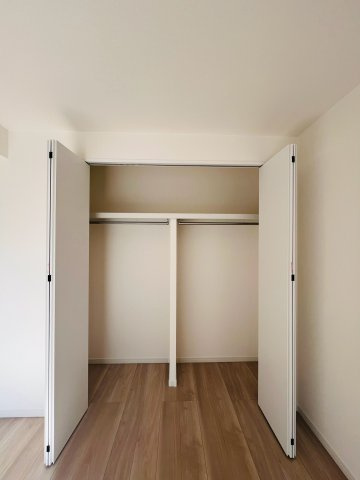 洋室（約6.0帖）：ハンガーパイプと上部棚を備えた便利な収納スペース。衣類をすっきりと整理できます。