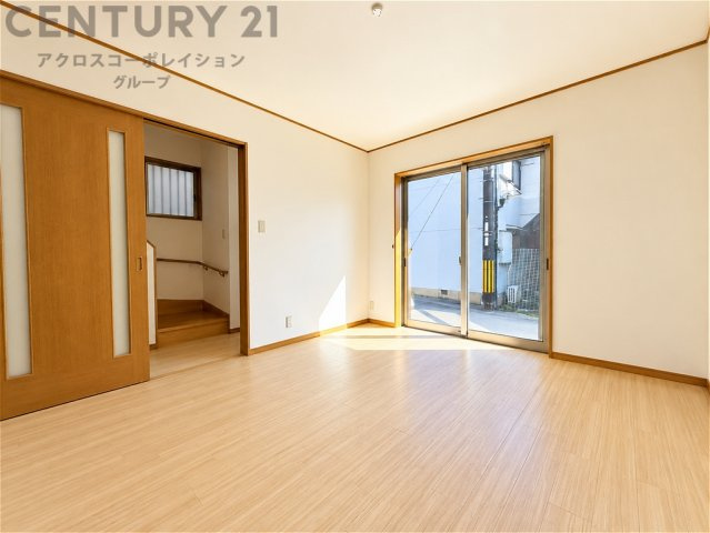 大きな窓から明るい陽射しが差し込む、開放感のある居住空間。ナチュラルな木目調の床が温かな雰囲気を演出します。家具の配置もしやすく、ご家族でゆったりとくつろげる心地よい空間です。