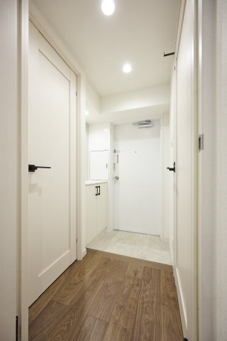 ダウンライトを備えた白を基調とした玄関スペース。お部屋へと続く、木目調のフローリングと、無駄のないミニマルなデザインが、洗練されたクオリティを予感させます。各居室への動線もスムーズです。