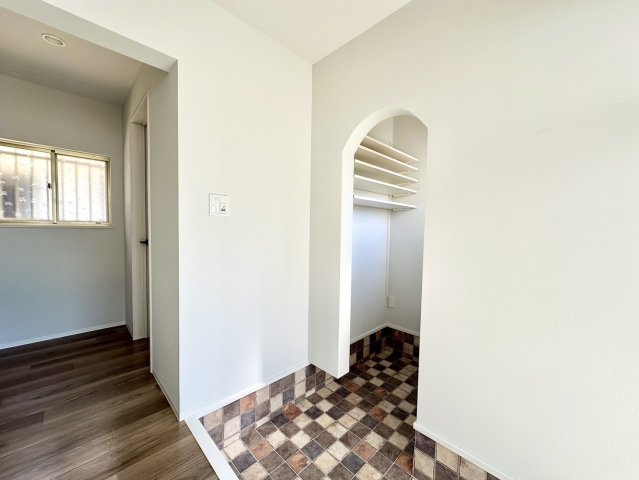 玄関にはおしゃれなアーチ開口。アーチ部分の曲線は、柔らかく、室内を暖かい印象にしてくれます。玄関のタイルも暖色で可愛いですね。玄関の壁には可動式の棚があり、靴や外出用の小物の高さを揃えて収納できます。