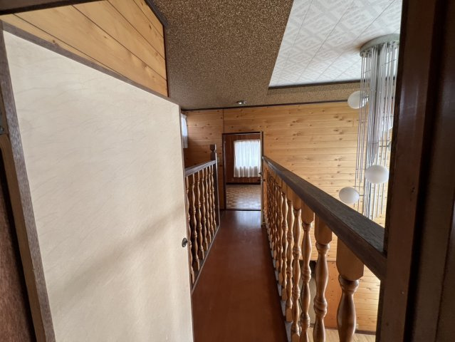 吹き抜けに面した2階の廊下。木製の手すりや板張りの壁が趣ある雰囲気を醸し出しています。1階を見渡せる開放的な設計で、上下階のつながりを感じられるのもポイント。木の質感を存分に楽しめる空間です。