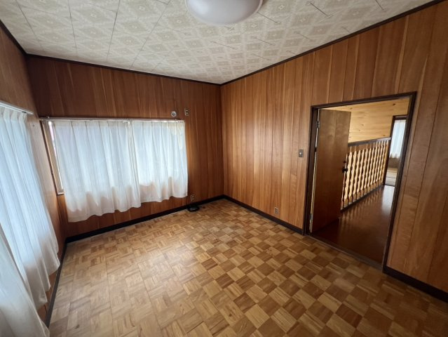 木目を活かした内装が印象的な2階洋室。複数の窓が設けられており自然光を取り込みやすい明るさのある空間です。特徴的な木製フローリングと壁面が温かな雰囲気を演出。寝室や趣味のお部屋など幅広く活用できます。