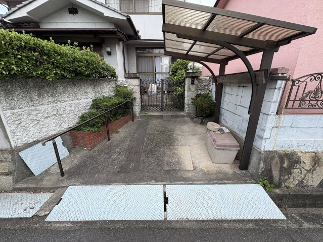 玄関前にはカーポート付きの駐車スペースがあり、大切なお車を雨や日差しから守ります。手すりも設置されており、ご高齢の方や小さなお子様も安心して利用できる設計です。玄関までのアプローチはフラットです。