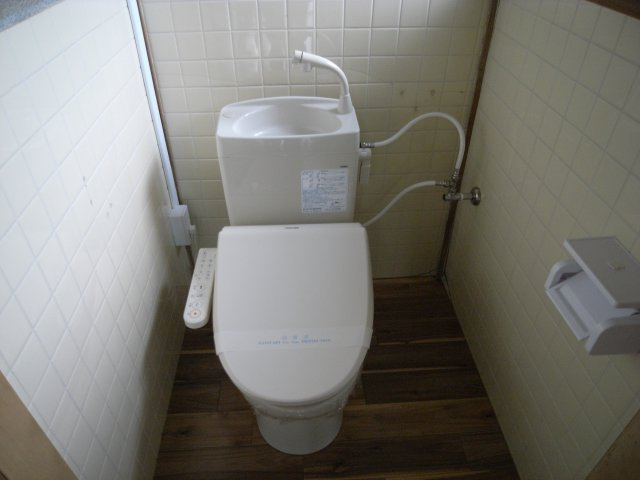 温水洗浄便座付きのトイレは、快適さと清潔さを兼ね備えた空間です。手洗い一体型タンクが設置されており、省スペースながら機能的に利用可能。床や壁のタイルが清掃しやすく、日々のお手入れも簡単なのが魅力です。