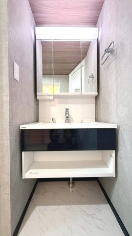 淡いグレーのクロスと三面鏡が調和する、ホテルライクな洗面所。収納力とデザイン性を備えた上質な空間です