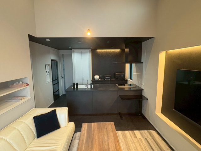 吹き抜けのある開放的なリビングは、自然光がたっぷり差し込み、明るく心地よい空間。落ち着いた色調と間接照明が上質な雰囲気を演出します。テレビ背面にはアクセントウォールを設け、デザイン性と居心地を両立。