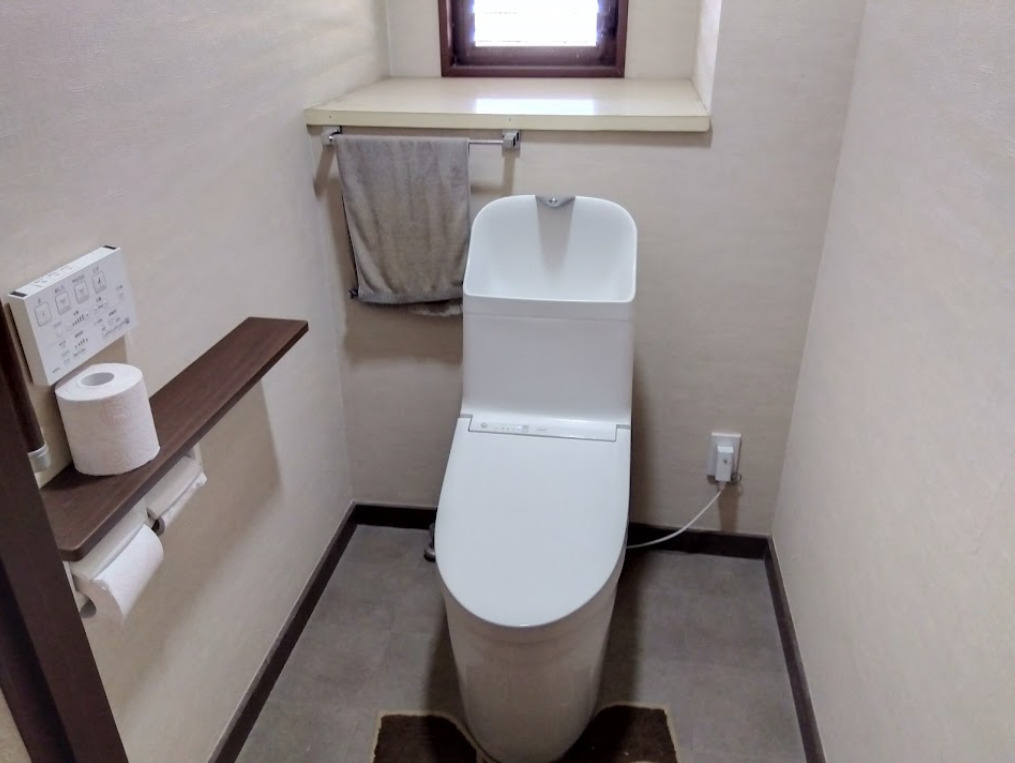 清潔感のある温水洗浄便座付きトイレです。操作パネルは壁付けタイプで使いやすく、毎日の生活を快適にサポートします。小窓付きのため自然換気が可能で、明るさと通風を確保できる点も嬉しいポイントですね。