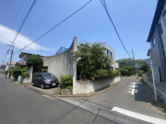 道路からの視線をゆるやかに遮る曲面壁。植栽の緑が映える、街並みに調和したモダンな意匠です