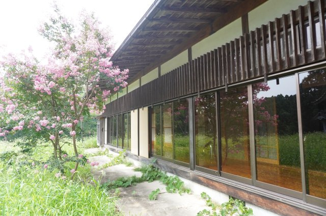 木造の深い軒下と庭の植栽が調和した、落ち着きある平屋の外観