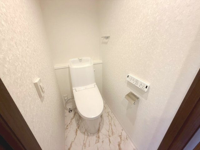 温水洗浄機能付きトイレは白を基調とし、大理石調の床が爽やかな印象です