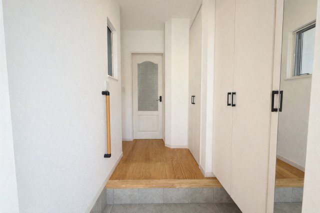 明るく清潔感のある玄関スペース。大容量のシューズボックスを備えご家族分の靴もすっきり収納可能です。窓があり自然光が入り圧迫感を感じにくい設計。手すり付きで小さなお子様やご高齢の方にも配慮されています　