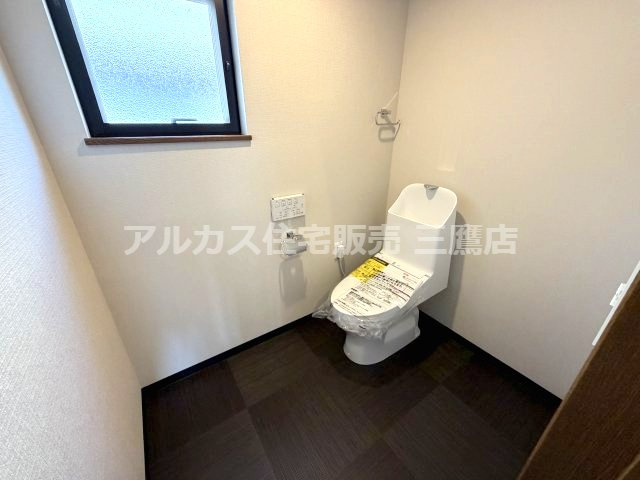 落ち着いたシックな床面デザインとホワイトの壁面が調和した、広さにゆとりのあるトイレ空間。