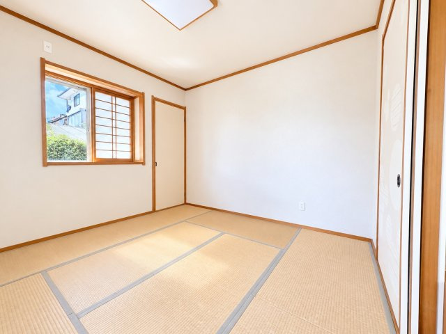 木目の建具と畳の温かみが調和する、落ち着いた雰囲気の8帖の和室です。窓から自然光が差し込み、明るく心地よい空間が広がります。リビングに隣接しており、引き戸を開放することでLDKと一体的に利用できます。