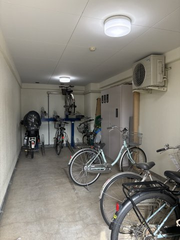 天候の影響を受けにくい、屋根と壁に囲まれた敷地内の駐輪スペースです。2段式ラックや平置きスペースが整然と配置されており、夜間でも明るい照明付きで出し入れがスムーズ。毎日の快適なフットワークを支えます。