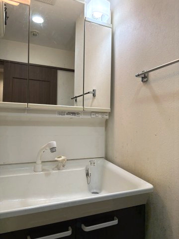鏡面が大きく見やすい3面鏡洗面台です。洗面ボウルは深さがあり、手洗いやお掃除も快適。上部には照明、右側にはタオル掛け、足元には小物をすっきり収納できる引き出しがあり、使い勝手の良い設計です。