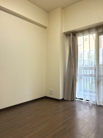南側のバルコニーに面した、日当たり良好な洋室です。大きな窓からは専用庭の植栽が優しく覗き、室内にいながら四季の潤いを感じられます。寝室や子ども部屋、書斎など多目的に使いやすい空間です。