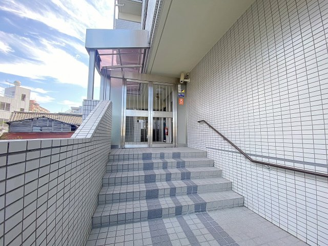 訪れる方を上品にお迎えする落ち着いた雰囲気のエントランス入口アプローチです。手入れが行き届いた植栽と洗練された外観デザインが、マンション全体の管理体制の良さを物語ります。