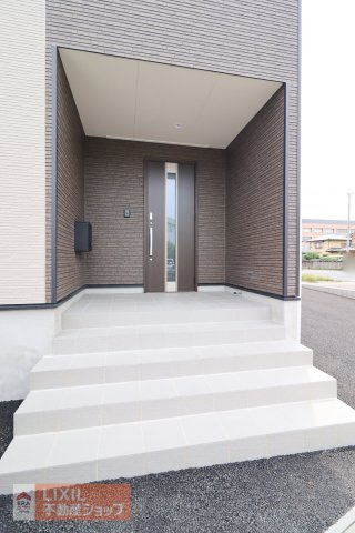 【エントランス／現地完成写真】屋根付きのポーチを採用して、雨の日に配慮。宅配ボックス設置をおススメ。