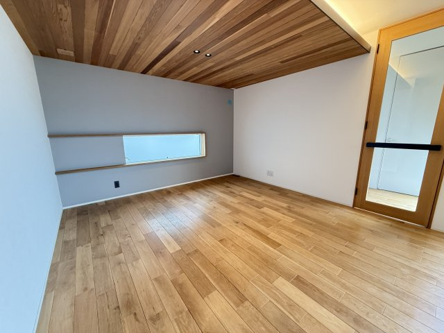 木目天井と間接照明が印象的なリビングは、温かみと上質さを兼ね備えた空間。足元まで光が届く窓で明るさも確保され、開放感があります。壁面の横長窓がアクセントとなり、デザイン性も良好で心地よい住空間です。