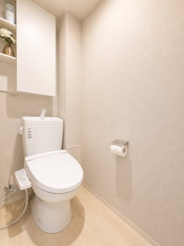 温水洗浄便座付きトイレ。上部収納も備え、トイレットペーパーや掃除用品をすっきり収納できます。清潔感あふれるシンプルなデザインです。