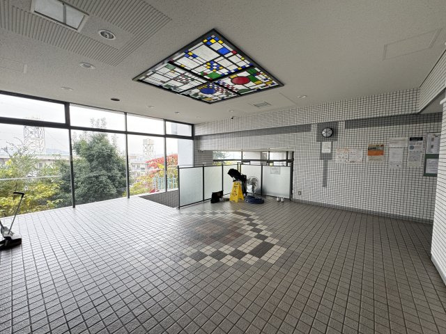 大きな窓から自然光が入るタイル張りの明るいエントランスで、共用部全体が清潔に保たれています。　出入り口がしっかりと区分されていることで、防犯面や生活動線が整えられていると感じられる作りです。