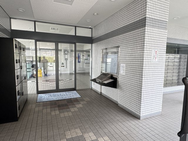オートロックや宅配ボックスの設備が見やすく配置されている広々としたエントランス空間は、ゆとりを感じられるつくりになっています。　床面や壁面のタイルが明るく、全体的に清潔感があります。