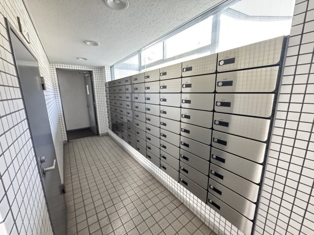 郵便受けは管理が行き届いた印象で、入居者の生活を支える安心感があります。　外からの光が差し込む廊下に設置されているため、荷物の取り出しがしやすい環境です。気持ちよく利用できる共有スペースですね。