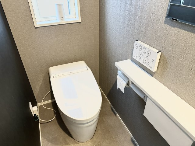 スタイリッシュなグレートーンの内装が印象的なトイレ空間。温水洗浄便座や壁付けリモコンなどの機能が備わっており、快適性と清潔感を両立。小窓付きで換気も良く、においや湿気の心配もありません。
