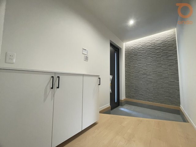 【ondo建物プラン例/玄関】石調のアクセント壁が目を引く玄関スペース。足元まで統一感あるカラーでまとめ、間接照明が陰影をやわらかく際立たせる上品な玄関です。
