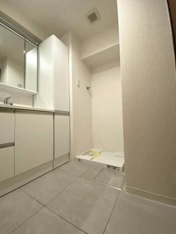 脱衣所　洗面化粧台や洗濯機置き場がまとまった機能的なパウダールーム。入浴時の着替えや朝の身支度動線がスムーズで、毎日快適にお使いいただける清潔感あふれる使いやすいレイアウトです