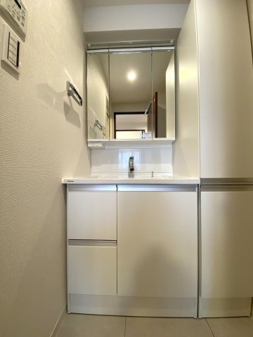 洗面台新規交換　新規交換された清潔感あふれる独立洗面化粧台。朝の身支度もスムーズに行えるワイドな鏡面と機能的な収納スペースを備えています。洗濯用水栓や防水パンも新調済みで安心です。