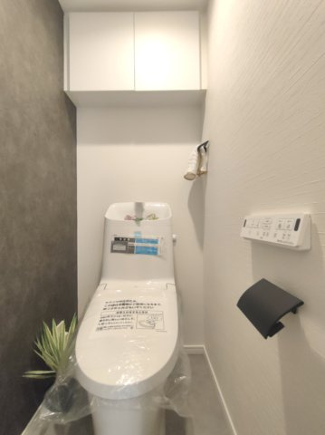 【トイレ】　温水洗浄便座・壁付けリモコン付き。吊り戸棚を備えた機能的なトイレです。