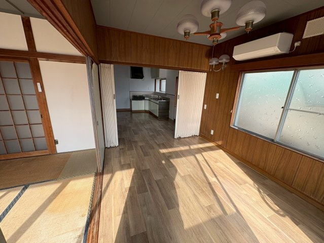 大きな窓からたっぷりと陽光が差し込む明るい洋室です。木目調の内装が落ち着いた雰囲気を演出し、ゆったりとした時間を過ごせます。隣室との引き戸を開ければ空間を広く使うことも可能となっています。