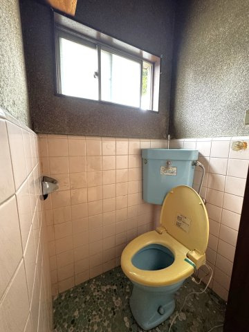 上部に大きめの引き違い窓が設置されており、いつでもスムーズに自然換気が行える衛生的なトイレ。床の玉石タイルも味わい深く、小物をアンティーク調に変えて、自分だけの空間に仕上げるのも素敵です。