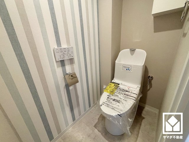 明るく清潔感溢れるトイレです。トイレットペーパーのストックや消耗品置き場などとしてお使いいただける吊戸棚がございます。