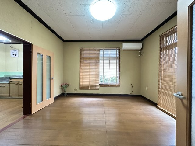 1階にあるゆったり8帖の洋室です。2面採光で明るく、木目調のブラインドが落ち着いた雰囲気を演出。隣のキッチンへ直接アクセスできる便利な間取りで、リビングとしても寝室としても多用途に使えます！