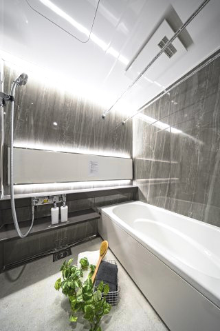 高級感漂う石目調パネルと間接照明が、一日の疲れを優しく癒やす。広々とした浴室。