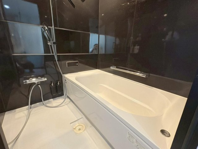 ブラックを基調とした高級感あふれる浴室は、ホテルライクな雰囲気が魅力です。ゆったりとした浴槽で一日の疲れを癒せるリラックス空間です。浴室乾燥機を備えており、雨の日の洗濯にも便利です。