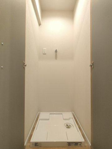 【室内洗濯機置き場】　洗面所ではなく、廊下の先に独立して洗濯機置き場がございます。室内の雰囲気を損なわないよう隠せるうえに、稼働中の音を聞こえにくくする扉付きです。