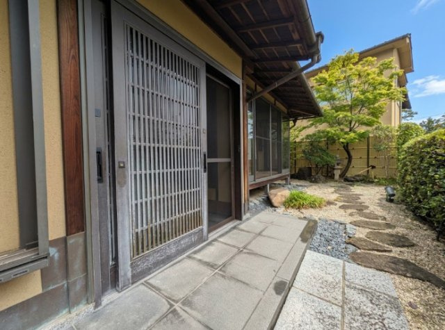 縦格子をあしらった引き戸が印象的な、趣ある玄関まわり。塗り壁が建物全体の和の意匠と調和し、落ち着いた佇まいに仕上がっています。外からも土間や庭の気配を感じられ、日本家屋ならではの風情が感じられます。