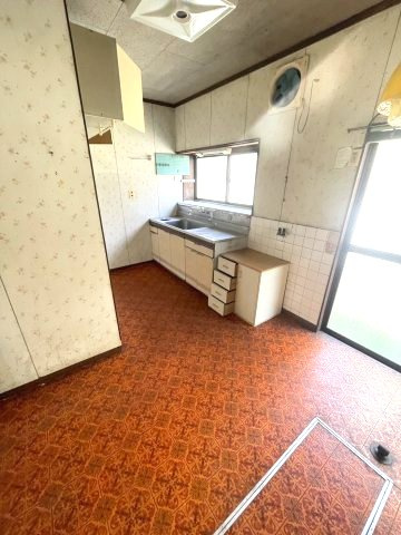 収納棚があり、手元を照らす窓と勝手口を備えたキッチン