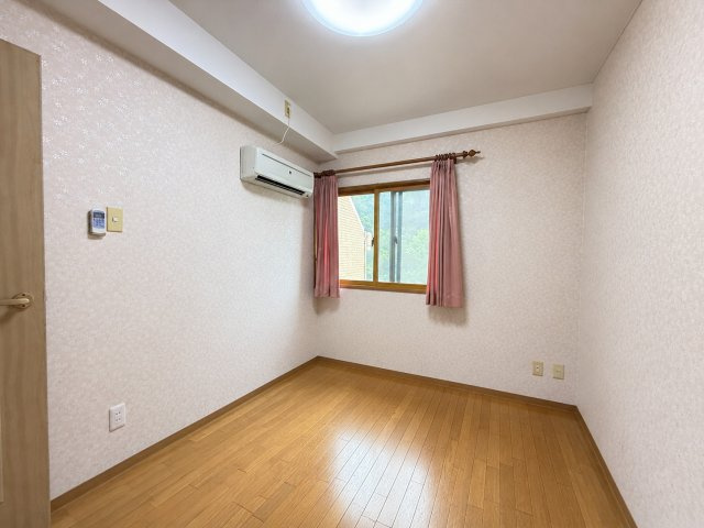 落ち着いた色合いでまとめられた洋室は、主寝室や子ども部屋としても使いやすい空間です。窓から自然光が入り、明るく心地よい雰囲気を演出します。シンプルな間取りで家具配置もしやすい設計です。