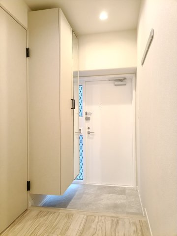 【玄関】　白でまとめられた清潔感のある玄関。住戸の顔として、いつでも整えておきたい空間に嬉しい大容量の収納がございます。姿見付きなので、お出かけ前に身支度のチェックができます。