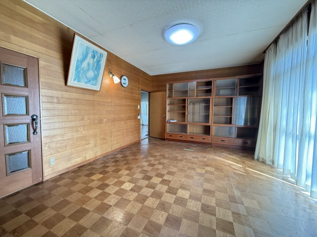 大きな窓から柔らかな自然光が差し込み、室内を明るく心地よい空間にしています。木目調の壁が温かみを感じさせ、落ち着いた雰囲気を演出。隣接する和室ともつながり、広々とした使い方ができるのも魅力です。