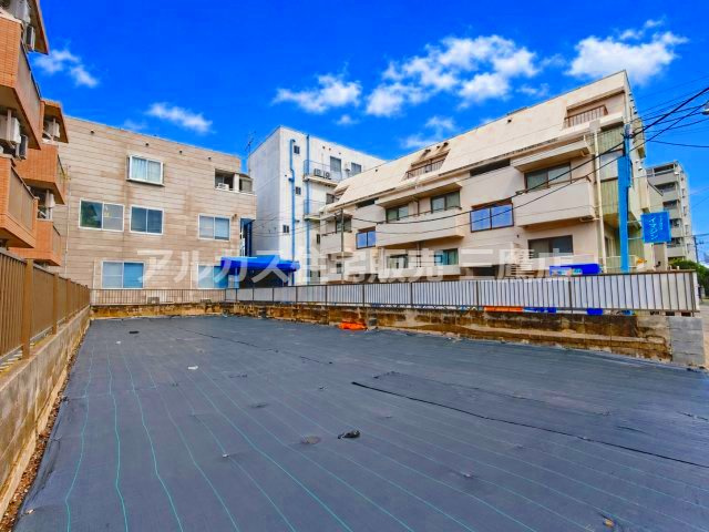 奥行きのある広々とした現地写真。周囲には建物が立ち並び、住環境のイメージが湧きやすいロケーションです。