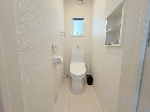 白を基調とした清潔感のあるトイレ空間です。温水洗浄便座付きで快適にご利用いただけます。収納棚も備わっており、トイレットペーパーや掃除用品をすっきり収納可能です。シンプルで飽きのこないデザインです。